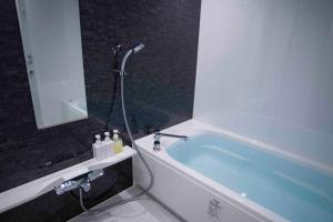 bagno con vasca e specchio di Shinjuku Miyabi Residence - Vacation STAY 94836 a Tokyo