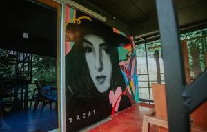 Lodge Phang nga boutique في Ban Khaek: لوحة لامرأة على جانب المبنى