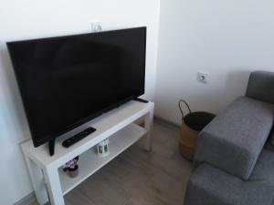 een flatscreen-tv op een witte stand naast een stoel bij Apartman REA 1 in Pirot