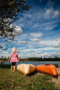 een klein meisje naast twee boten in het gras bij Brightstone Lake Cabin 1 in Fair Oaks