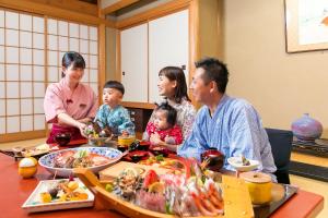 a family sitting at a table eating food at Hotel Kan-ichi in Atami