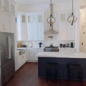 a kitchen with white cabinets and a blue island at Walk to French Quarter Canal Suite Guesthouse in New Orleans