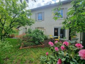 une maison avec des fleurs roses dans la cour dans l'établissement Gîte Saint-Galmier, 3 pièces, 4 personnes - FR-1-496-292, à Saint-Galmier