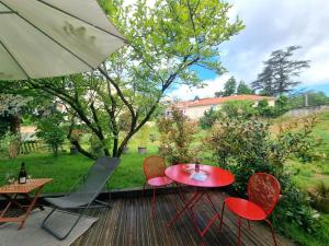 un patio con tavolo, sedie e ombrellone di Gîte charmant avec jardin, terrasse et tout confort à Saint-Galmier - FR-1-496-293 a Saint-Galmier