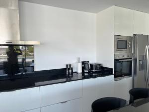 uma cozinha com paredes brancas e um balcão com electrodomésticos em Villa de luxe avec amarre Rosas em Roses