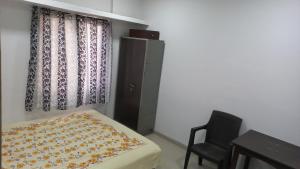 a small bedroom with a bed and a chair at The Nest - Harmony Inn in Sangli
