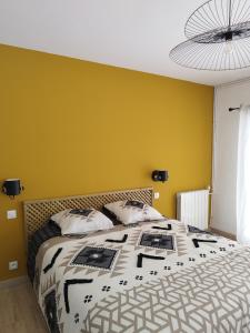 um quarto com uma cama grande e uma parede amarela em Domaine de l'Arbre Doré em Lèzan