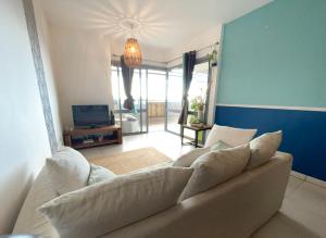 a living room with a white couch and a television at Le Cocon Appartement Vue Mer et Montagne in Sainte-Marie