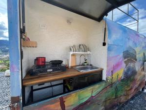 una cocina con fregadero y una pintura en la pared en Glamping Cielo Roto, en Sutamarchán