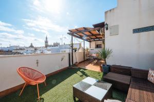 een dakterras met een bank en een tafel bij Amazing Penthouse Giralda Views 8 pax, Parking Optional in Sevilla