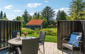 un patio con mesa, sillas y una valla en Beautiful Apartment In Blokhus With Kitchen, en Blokhus