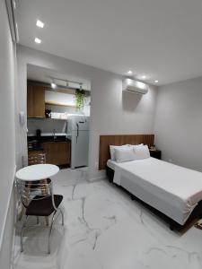 a bedroom with a bed and a table and a kitchen at C3 STUDIO in Rio de Janeiro