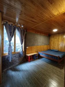 a room with a bed and a bench and windows at May Kim Ta Phin Homestay in Sa Pa