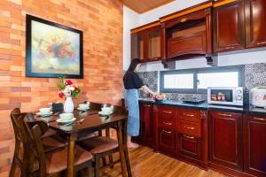 a woman standing in a kitchen with a table at IRIS HILL VILLA in Thôn Dương Xuân Hạ