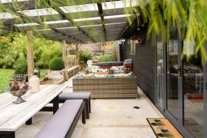 a patio with a table and benches and a couch at The Chefs Cottage in Waikanae