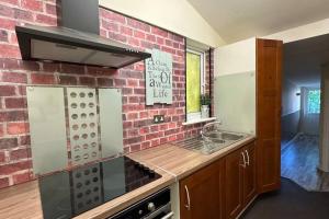 a kitchen with a brick wall and a stove top oven at Palaz 7 - 5 bedroom house in Edmonton