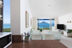 a white living room with a view of the ocean at Shoal Bay Shores, modern beachfront unit + Wifi in Nelson Bay