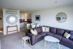 a living room with a purple couch and a kitchen at Shoal Bay Shores, modern beachfront unit + Wifi in Nelson Bay