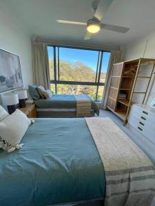 a bedroom with two beds and a large window at Shoal Bay Shores, modern beachfront unit + Wifi in Nelson Bay