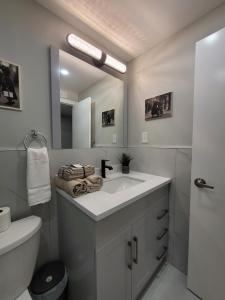 Baño blanco con lavabo y espejo en RoryHouse en Toronto