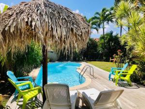 a pool with chairs and a straw umbrella at Villa TrÔpik Diamond + Bungalow in Le Diamant