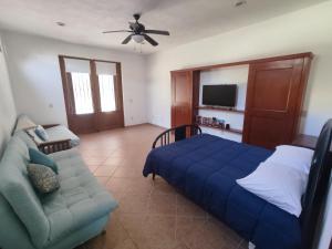 een slaapkamer met een blauw bed en een bank bij Casa las Palmas in Manzanillo