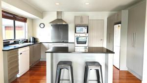 una cocina con una gran isla con dos taburetes en Stunning Family Home, en Auckland