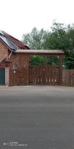 a barn with a wooden gate and a wooden fence at Kontra szálláshely in Sándorfalva