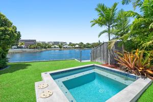 a swimming pool in a yard next to a body of water at Blue Lagoon Villas in Trinity Beach