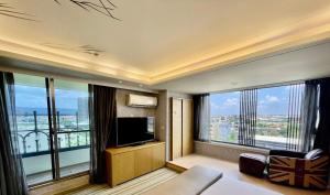 Habitación de hotel con TV y ventanas grandes. en Morn Sun Hotel en Changhua County