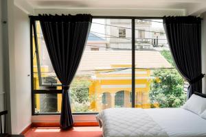 a bedroom with a bed and a large window at Be Them homestay in Hue
