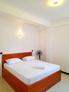1 dormitorio con 1 cama grande con sábanas blancas en Sky Heaven Hotel en Kandy
