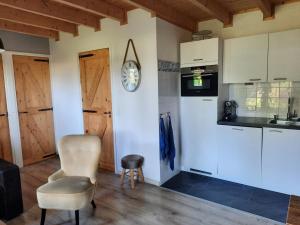 a kitchen with white cabinets and a chair at Chalet in Castricum