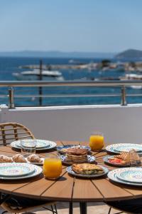 a wooden table with plates of food and orange juice at Nuovo Suite in Neos Marmaras