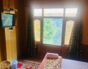 a room with a window and a bed and a television at Galaxy Inn by StayApart in Kūfrī