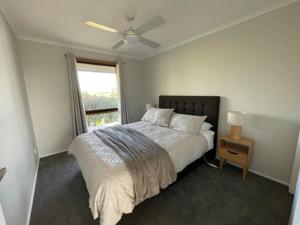 een witte slaapkamer met een bed en een raam bij Yering Park Cottage in Coldstream