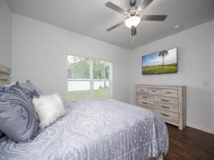 a bedroom with a bed with a ceiling fan and a dresser at Breezy Villa in Palm Coast