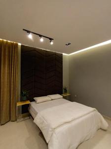 a bedroom with a large white bed with a wooden headboard at Beach Front Apartment in Salalah