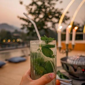 a hand holding a glass with a green drink at Baanpufa Resort in Sai Yok