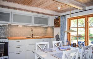una cocina con armarios blancos y una mesa con sillas. en 3 Bedroom Gorgeous Home In Borrby, en Borrby