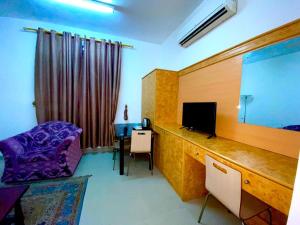 Zimmer mit einem Schreibtisch, einem TV und einem Stuhl in der Unterkunft Savoy Inn Hotel Apartments in Muscat