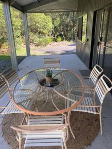 - une table en verre et des chaises sur une terrasse couverte dans l'établissement Austinville Hinterland Chalet, à Neranwood