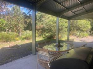 a patio with a glass table and chairs on a porch at Austinville Hinterland Chalet in Neranwood