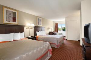 a hotel room with two beds and a flat screen tv at Days Inn & Suites by Wyndham Rancho Cordova in Rancho Cordova