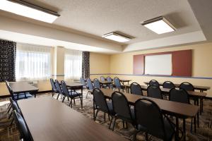 a conference room with tables and chairs and a screen at Days Inn & Suites by Wyndham Rancho Cordova in Rancho Cordova