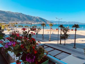 een uitzicht op een strand met palmbomen en bloemen bij Veranda Boutique Hotel in Vlorë