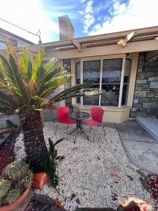 a patio with two chairs and a table in front of a house at West Beach House 4U in Henley Beach South