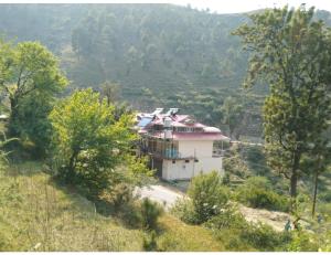 a house on the side of a hill with trees at Pine Wood Resort, Barkot in Barkot