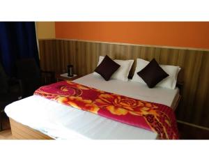 a bed with a red and yellow blanket on it at Pine Wood Resort, Barkot in Barkot
