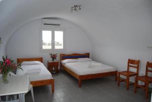 Habitación con 2 camas, mesa y sillas en Apollo Rooms, en Perissa